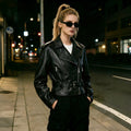 Women's short jacket in biker style made of soft faux leather with asymmetrical zip and waist belt